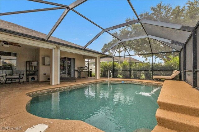 view of swimming pool with grilling area, a patio area, pool water feature, glass enclosure, and ceiling fan