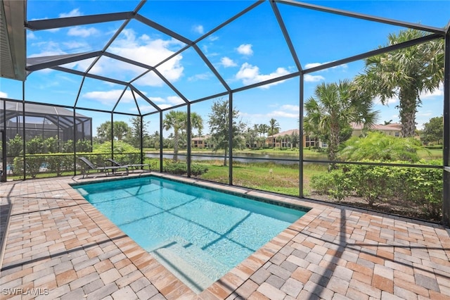 outdoor pool with a lanai, a patio area, and a water view