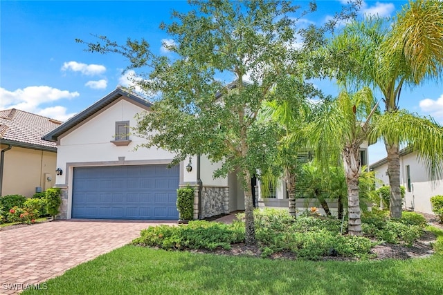 view of front of property with an attached garage, stone siding, decorative driveway, and stucco siding