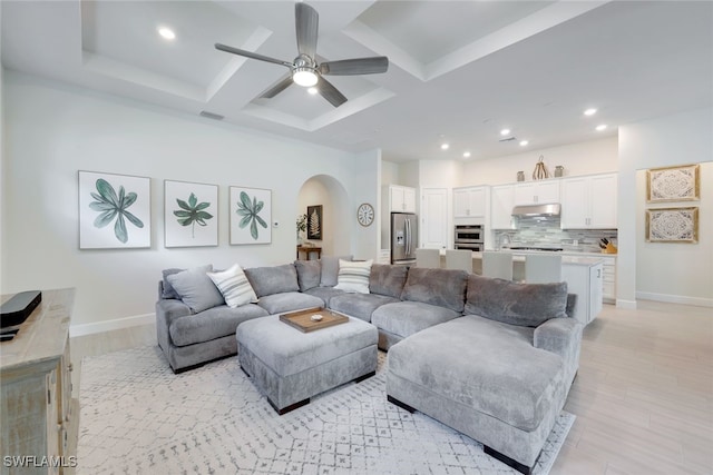 living room with visible vents, arched walkways, coffered ceiling, baseboards, and light wood-style flooring