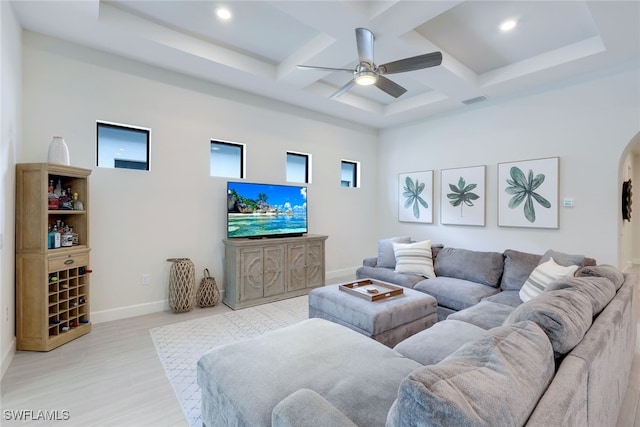 living area featuring arched walkways, light wood-style flooring, ceiling fan, coffered ceiling, and baseboards