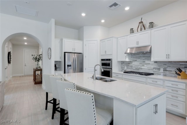 kitchen featuring arched walkways, visible vents, appliances with stainless steel finishes, a sink, and under cabinet range hood