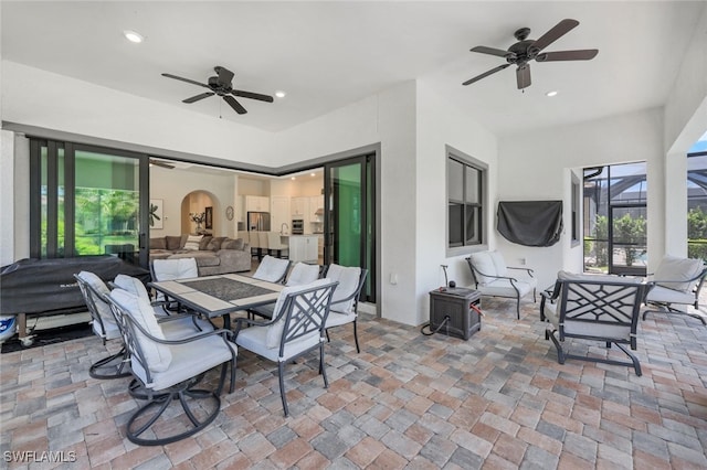 view of patio featuring glass enclosure, outdoor lounge area, a ceiling fan, and outdoor dining space