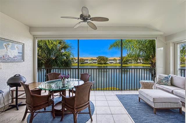 sunroom featuring ceiling fan, vaulted ceiling, and a water view