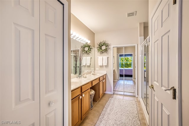 bathroom with tile patterned floors, a shower with door, and vanity