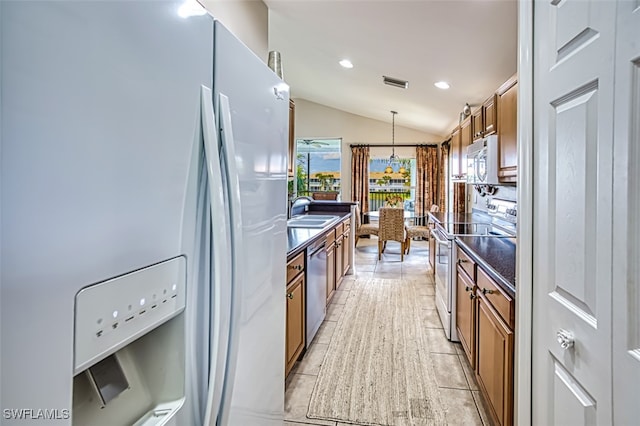 kitchen featuring lofted ceiling, sink, pendant lighting, and stainless steel appliances