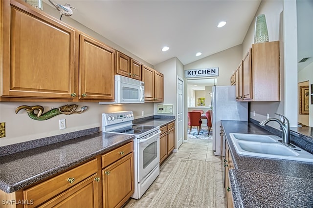 kitchen featuring light tile patterned floors, lofted ceiling, sink, and white appliances