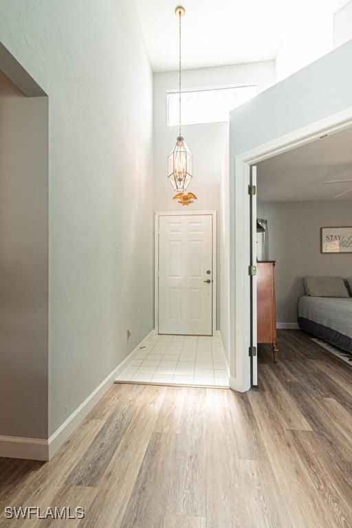 25202 Golf Lake Cir, Bonita Springs, FL 34135 - entrance foyer with baseboards, a high ceiling, light wood-style flooring, and an inviting chandelier