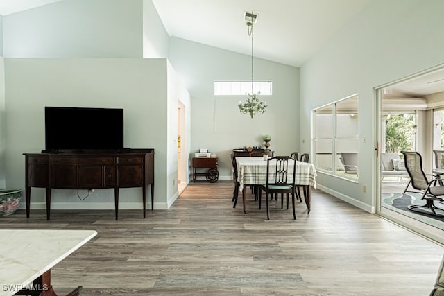 dining space with high vaulted ceiling and light hardwood / wood-style flooring