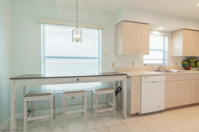 kitchen with light tile patterned flooring, decorative light fixtures, white dishwasher, and light brown cabinets