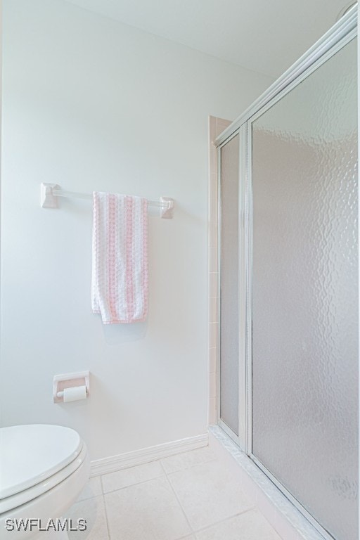 bathroom with an enclosed shower, tile patterned flooring, and toilet