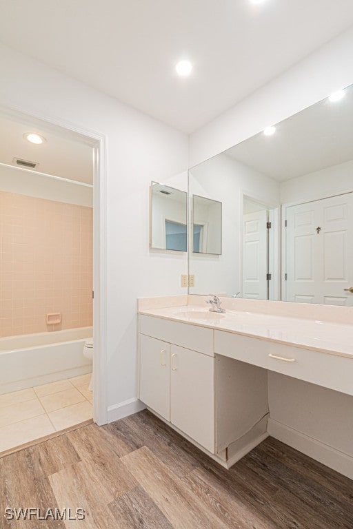 full bathroom featuring vanity, toilet, tiled shower / bath combo, and hardwood / wood-style flooring