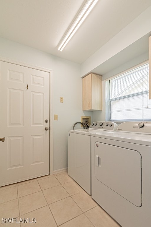 clothes washing area with washing machine and clothes dryer, cabinets, and light tile patterned flooring