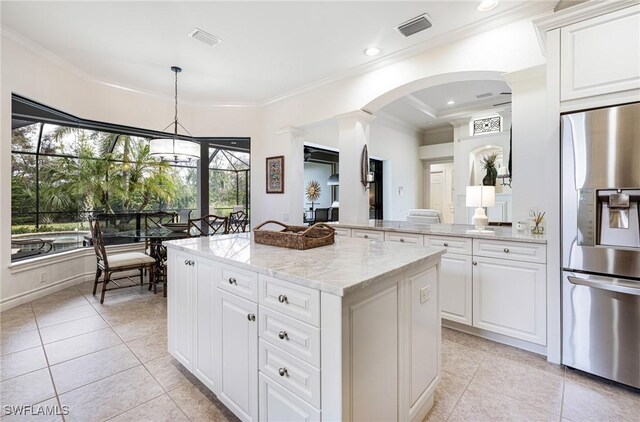 kitchen featuring hanging light fixtures, light stone countertops, a kitchen island, stainless steel refrigerator with ice dispenser, and white cabinets