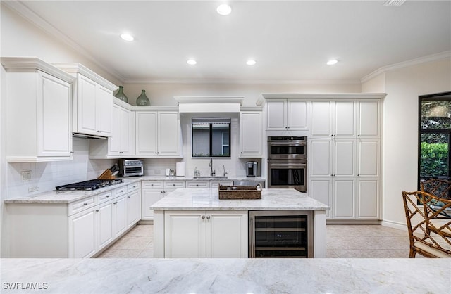 kitchen with light stone countertops, white cabinetry, wine cooler, and appliances with stainless steel finishes