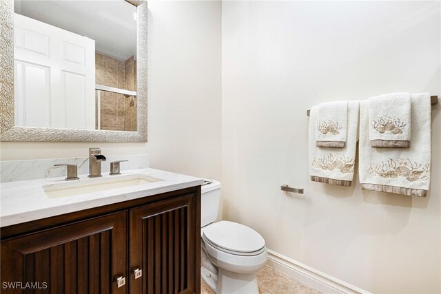 bathroom featuring toilet, tile patterned flooring, a shower with shower door, and vanity