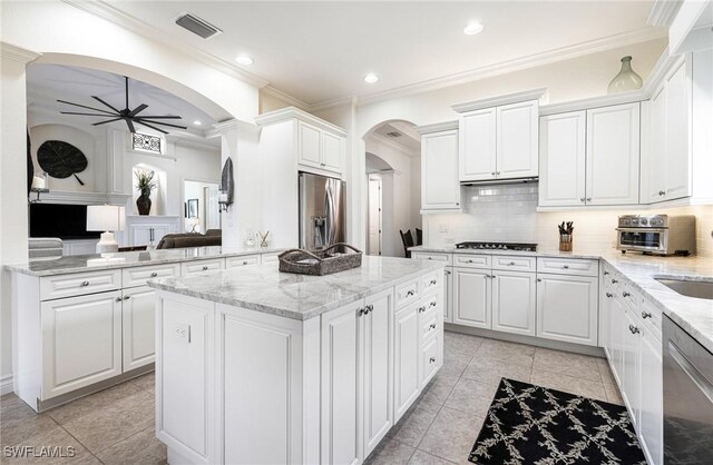 kitchen with stainless steel appliances, white cabinets, ceiling fan, tasteful backsplash, and a kitchen island