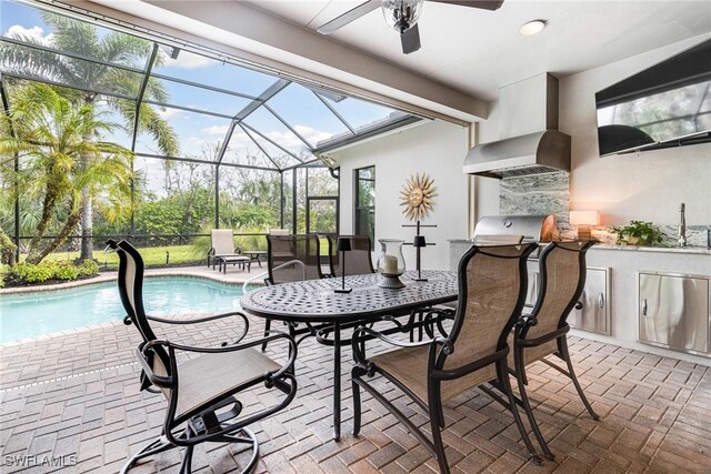 view of patio / terrace featuring exterior kitchen, ceiling fan, and glass enclosure