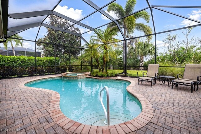 view of pool with glass enclosure, a patio area, and a pool with connected hot tub