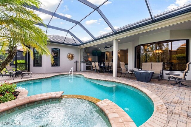 view of swimming pool with exterior kitchen, ceiling fan, a lanai, a grill, and a patio area