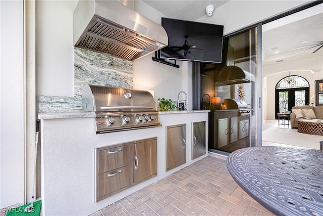 bar featuring wall chimney exhaust hood, brick floor, a sink, and a ceiling fan