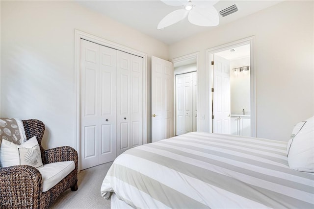 bedroom with ceiling fan, multiple closets, and light carpet