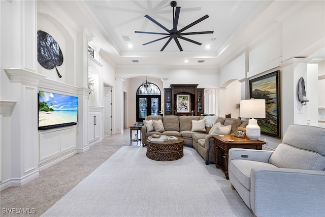 living room with a towering ceiling, a raised ceiling, ceiling fan, and french doors