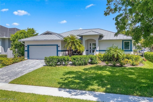 single story home with an attached garage, decorative driveway, stucco siding, a front lawn, and a standing seam roof