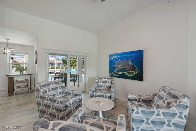 living area with a chandelier, wood finished floors, a wealth of natural light, and baseboards