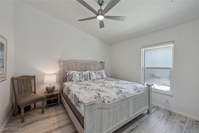 bedroom featuring light wood-type flooring, vaulted ceiling, baseboards, and ceiling fan