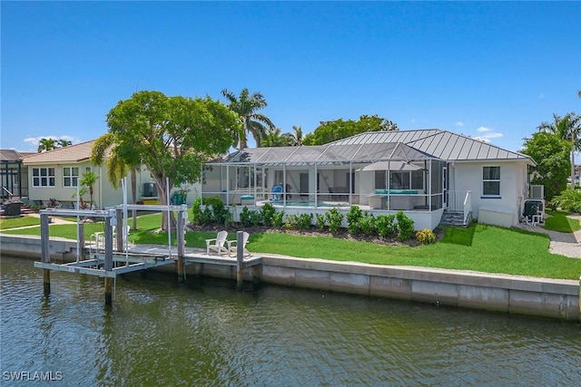 back of property featuring a lanai, a water view, a yard, and metal roof