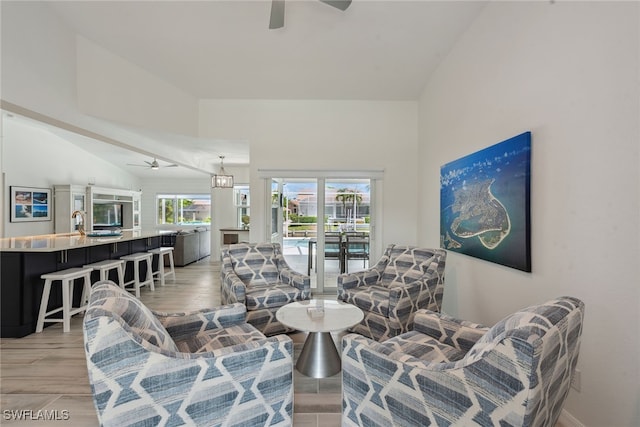 living room featuring high vaulted ceiling, ceiling fan, and light wood-type flooring