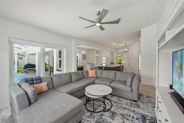 living room with sink, ceiling fan with notable chandelier, and light hardwood / wood-style floors