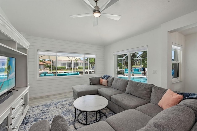 living room with a sunroom, ceiling fan, vaulted ceiling, and wood finished floors