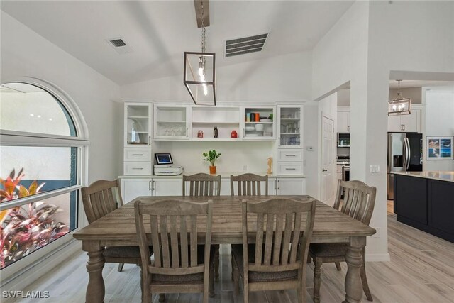 dining space featuring high vaulted ceiling, an inviting chandelier, and light wood-type flooring