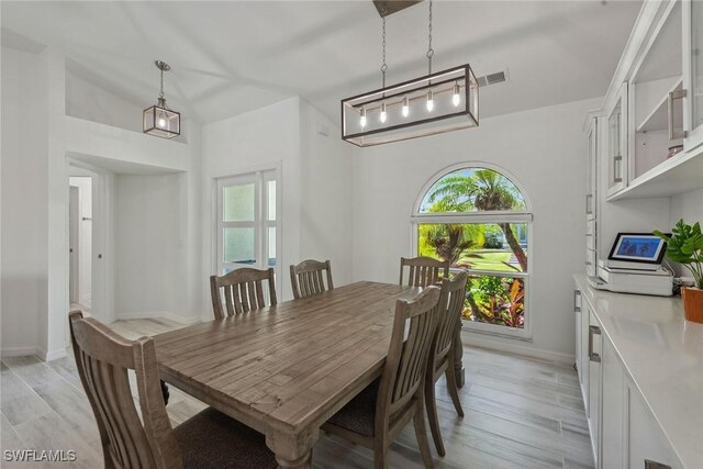 dining space featuring vaulted ceiling and light hardwood / wood-style flooring