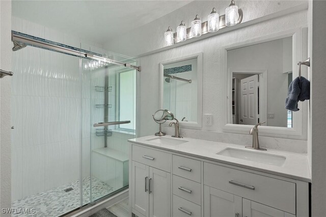 bathroom featuring a shower with door and vanity