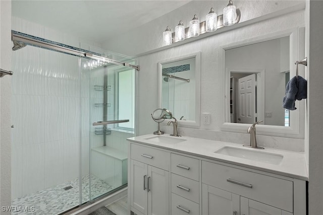 bathroom featuring double vanity, a stall shower, and a sink