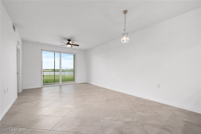 empty room with light tile patterned floors and ceiling fan with notable chandelier