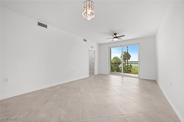 tiled empty room with ceiling fan with notable chandelier