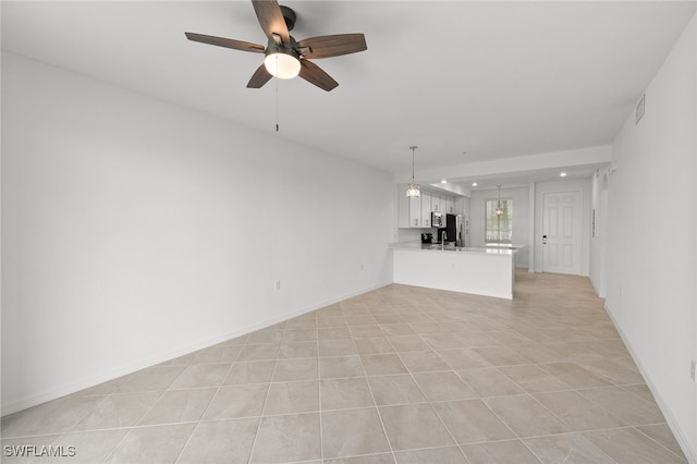 unfurnished living room featuring ceiling fan, sink, and light tile patterned flooring