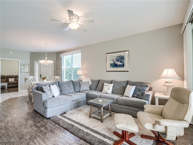 living room with ceiling fan with notable chandelier and light hardwood / wood-style floors