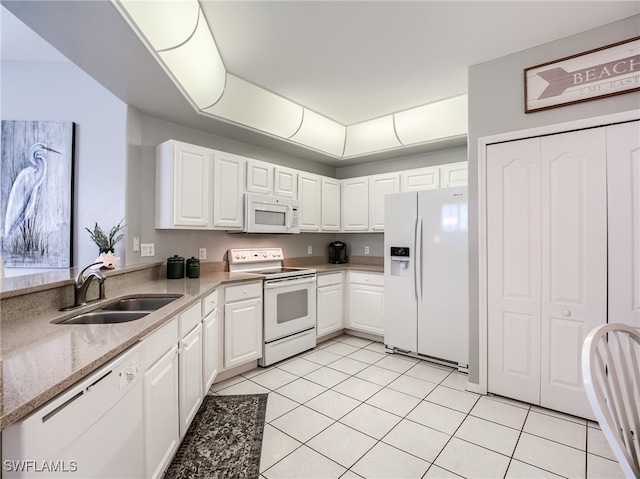 kitchen with light tile patterned floors, white appliances, sink, and white cabinets