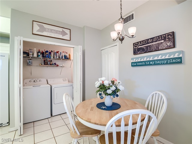 tiled dining area with separate washer and dryer and an inviting chandelier