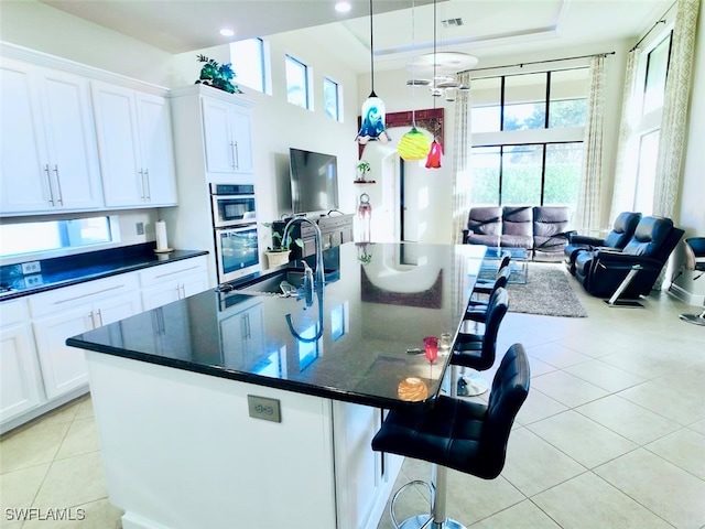 kitchen featuring a center island with sink, white cabinetry, sink, and plenty of natural light