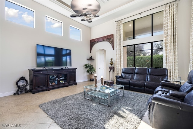 living room with light tile patterned floors, a towering ceiling, ceiling fan, and a healthy amount of sunlight