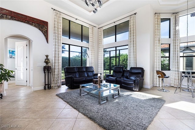 tiled living room featuring a towering ceiling, ornamental molding, and a healthy amount of sunlight