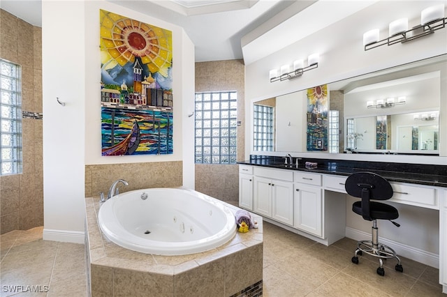 bathroom with tiled tub, vanity, and tile patterned flooring