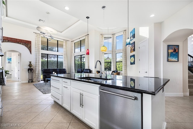 kitchen with hanging light fixtures, white cabinetry, an island with sink, stainless steel dishwasher, and sink