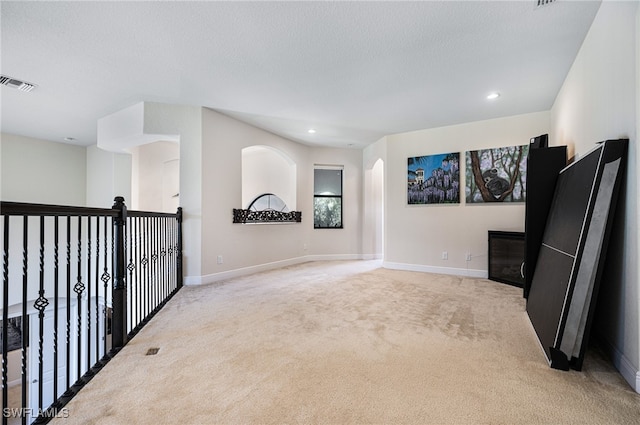 unfurnished room featuring light colored carpet and a textured ceiling